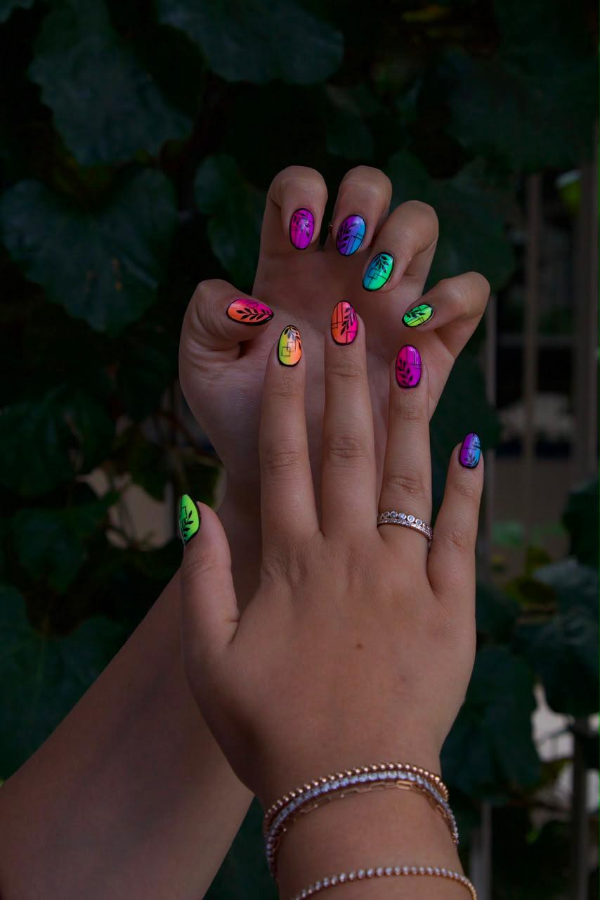 Neon gradient nails outlined with fine black leaf detail with leaf background